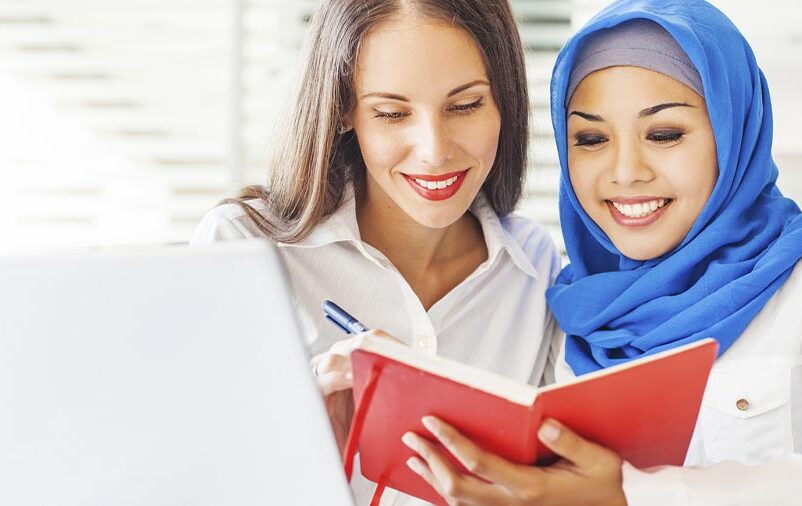 Cultura na tradução: mulher muçulmana mostrando um livro vermelho para tradutora